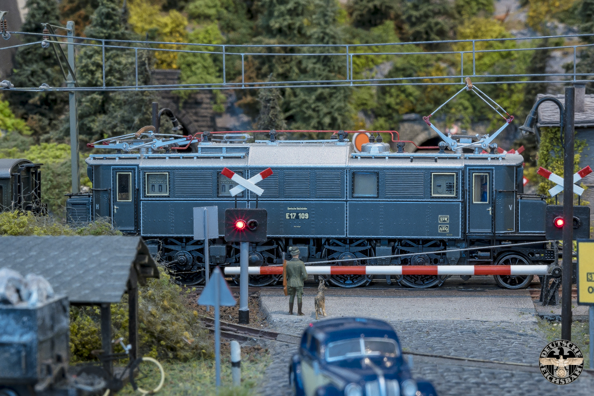 E17.109 passeert de spoorwegovergang bij het dorp.