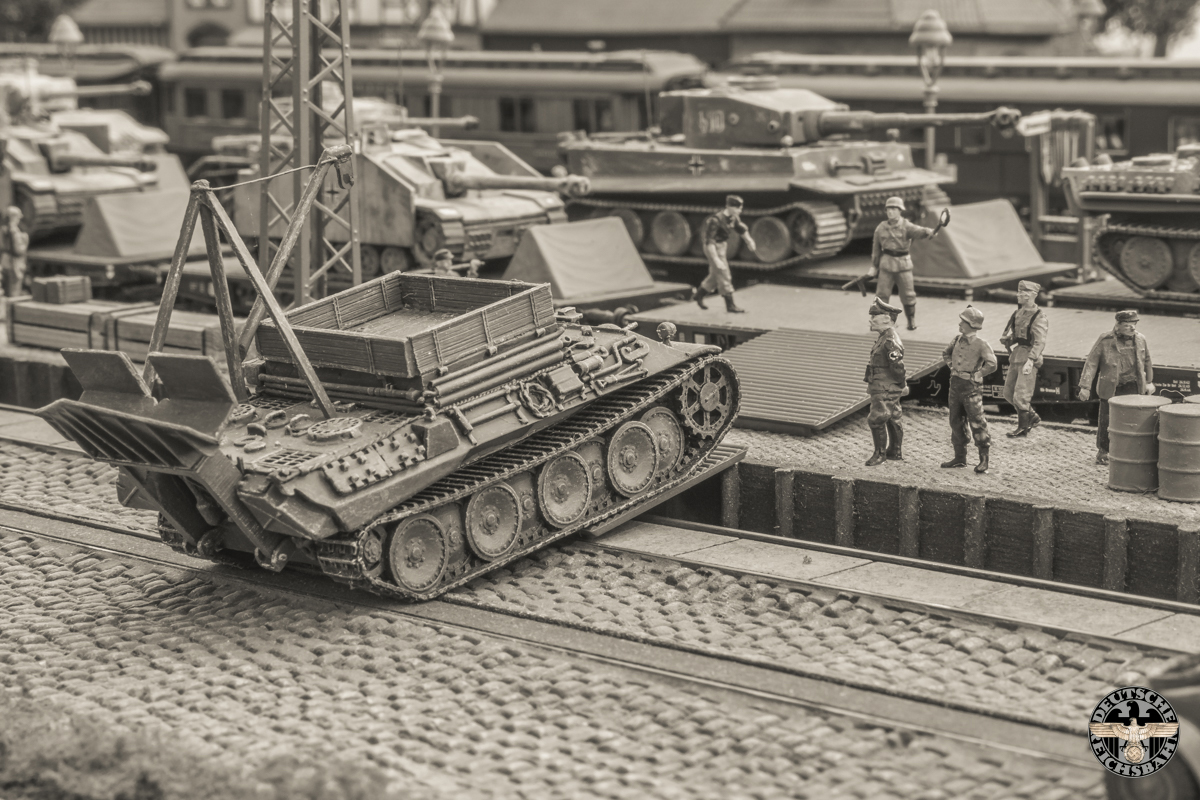 Men kijkt toe hoe het laatste voertuig op de wagon geladen wordt.